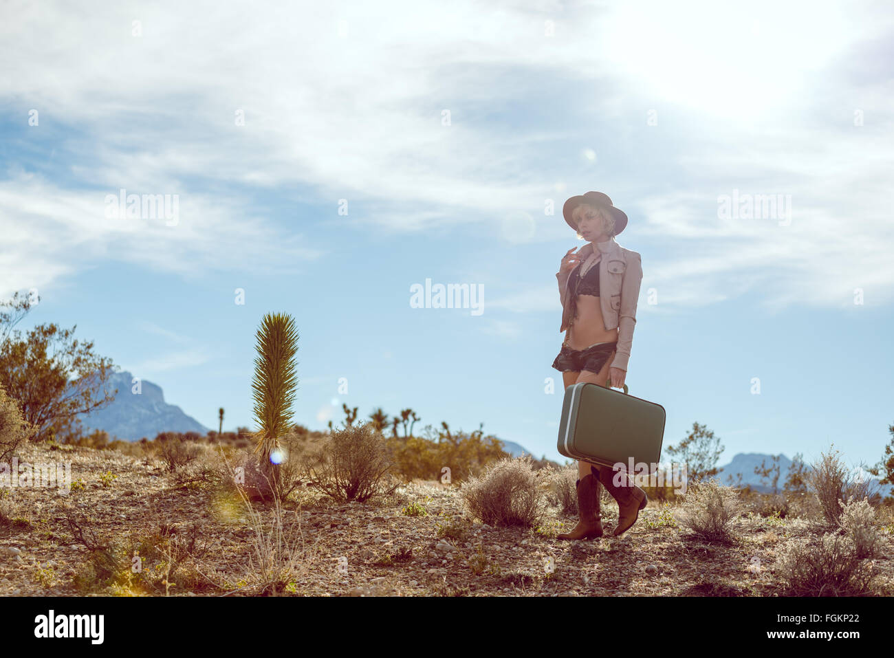 Moda Donna traveler camminando con la valigia e bagagli nel deserto Foto Stock