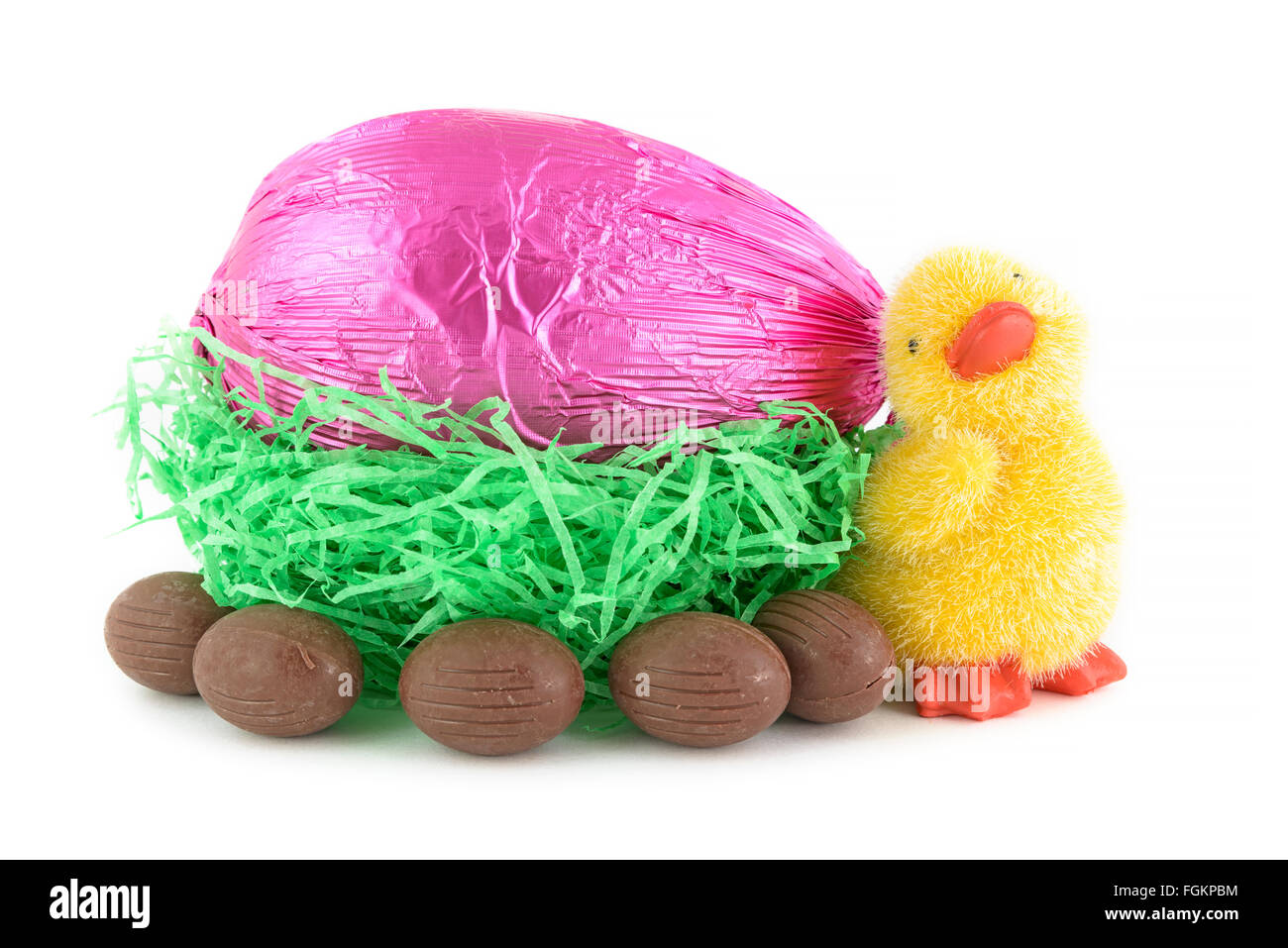 Toy pulcino e uova di pasqua di cioccolato nel nido isolato su sfondo bianco Foto Stock