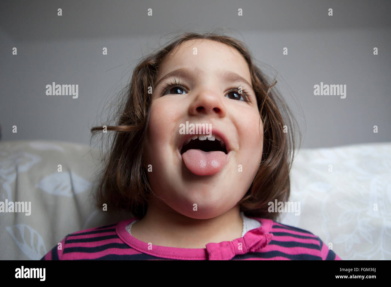 Joker tre anni bambina con la lingua di fuori. Ritratto in interni Foto Stock