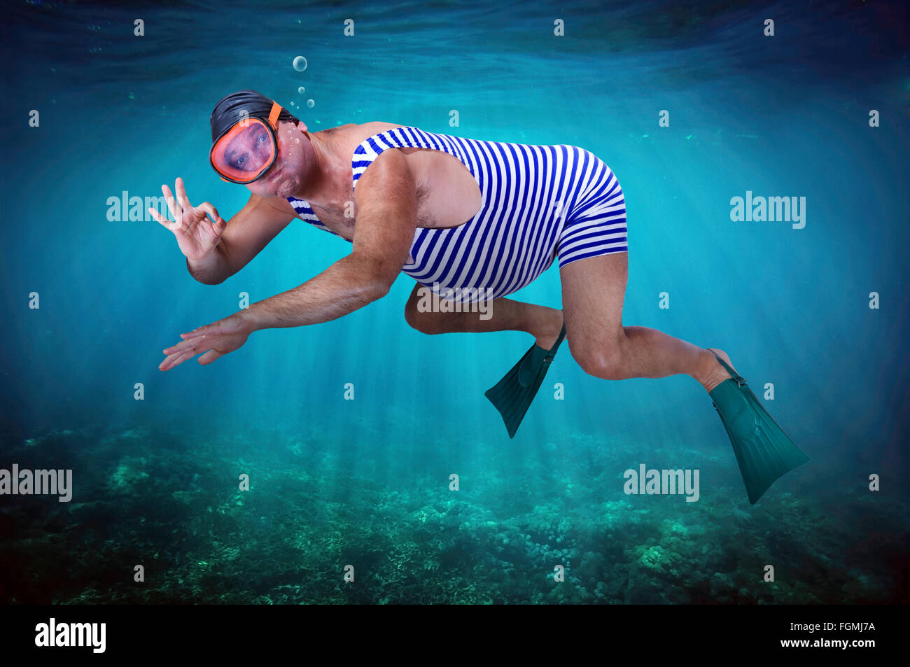Uomo in costume da bagno retrò nuota sott'acqua in mare Foto Stock