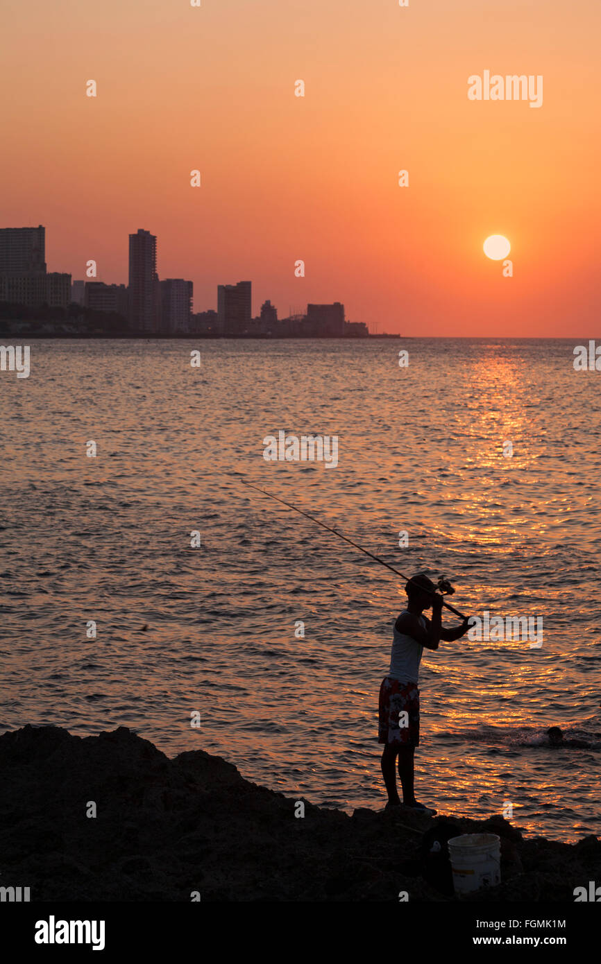 La vita quotidiana a Cuba - Locale cubano pesca maschio come il sole tramonta sul mare a El Malecon, Havana, Cuba, West Indies Caraibi America Centrale - tramonto Foto Stock