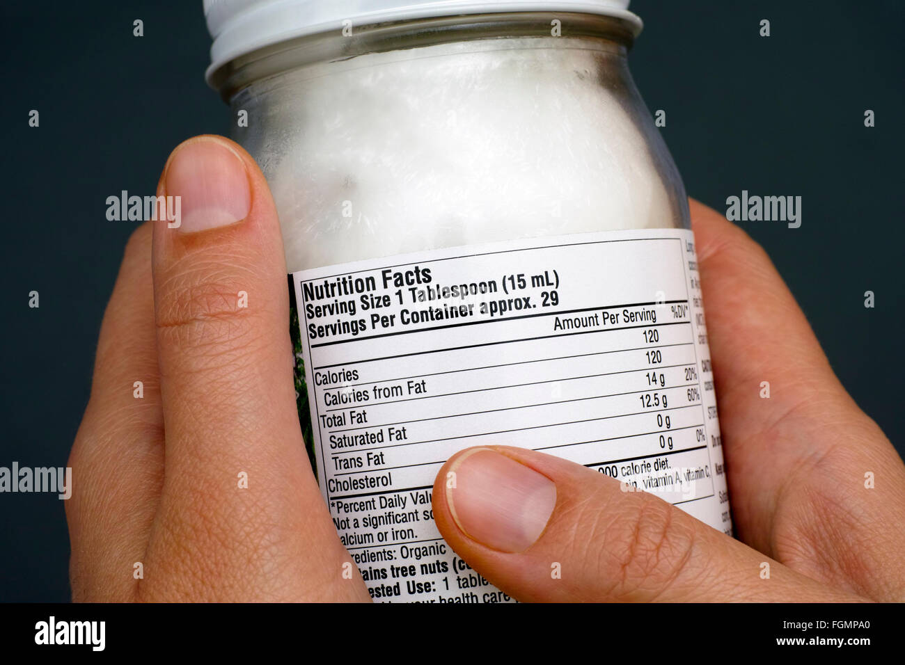 La lettura di un fatti di nutrizione organica di olio di noce di cocco jar. Close-up. Foto Stock
