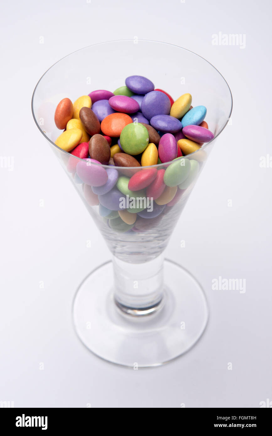 Bicchiere di vino pieno di cioccolato multicolore Smarties Foto Stock