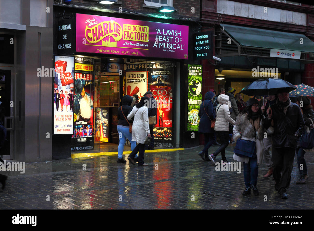 Le persone camminare davanti a un theatre ticket Booking office su una serata piovosa, vicino al Covent Garden di Londra, Inghilterra Foto Stock