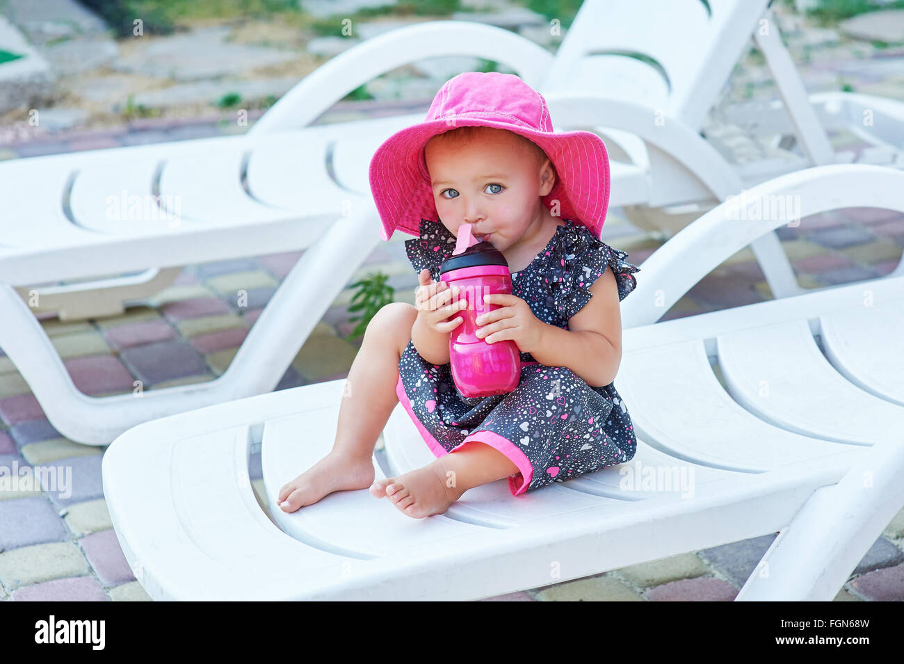 Little Baby girl in autunno park bevande da rosa la bottiglia di plastica Foto Stock