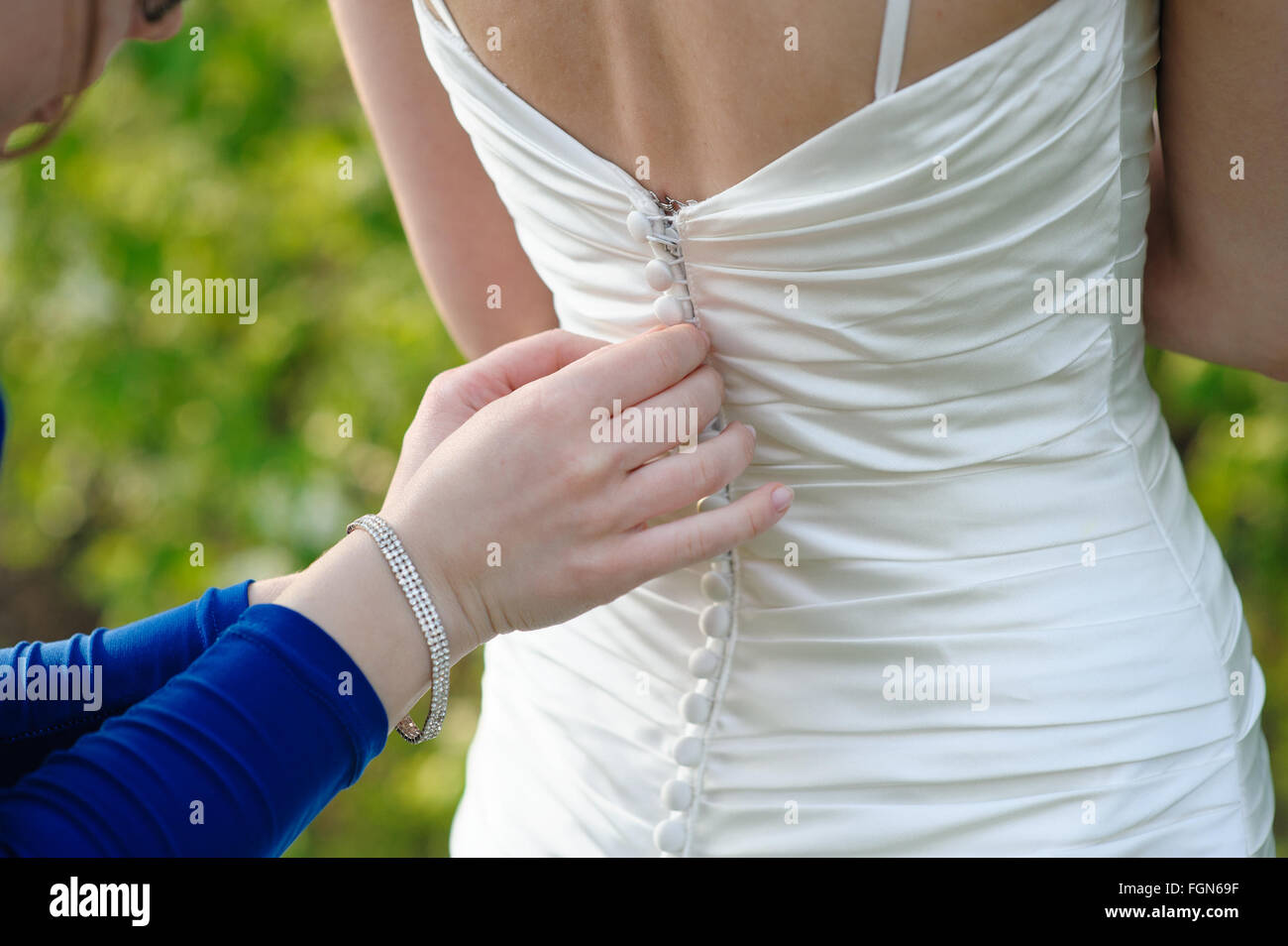 Damigella sta aiutando la sposa di vestire Foto Stock