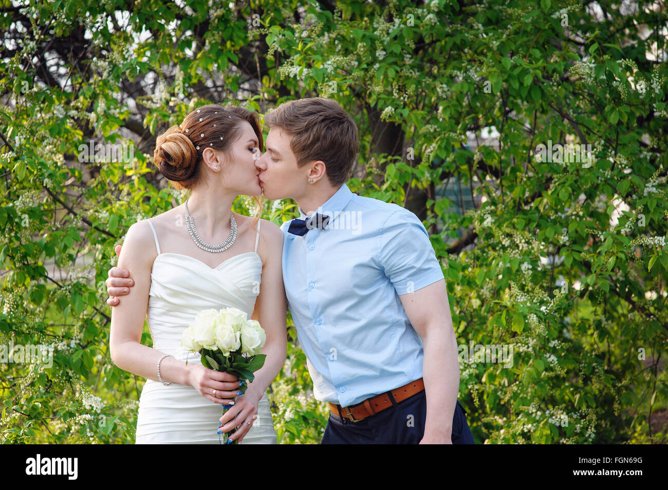 Sposa e lo sposo bacio nel giardino di primavera Foto Stock