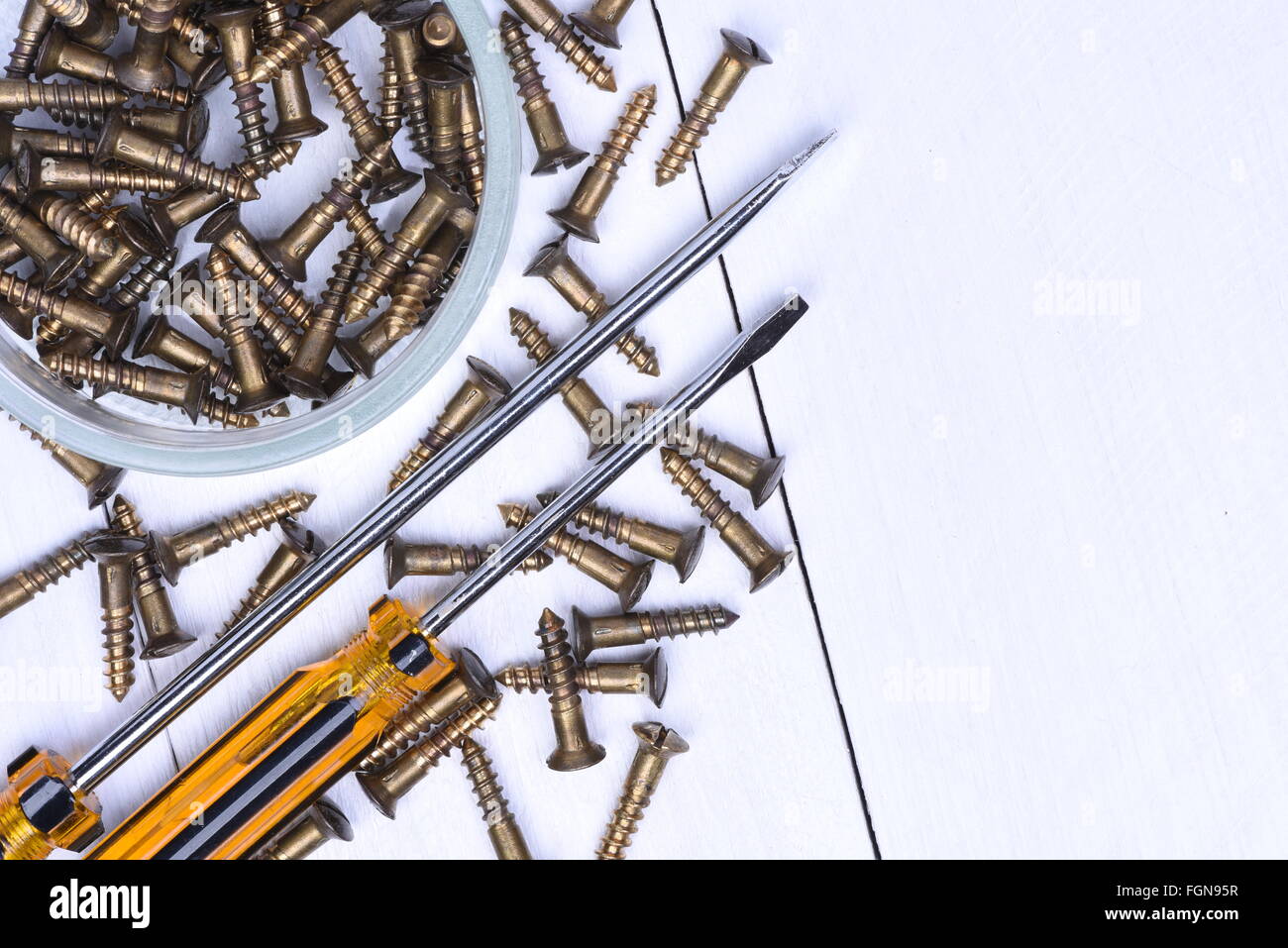 Scatola con viti in ottone e cacciaviti sul tavolo di legno Foto Stock