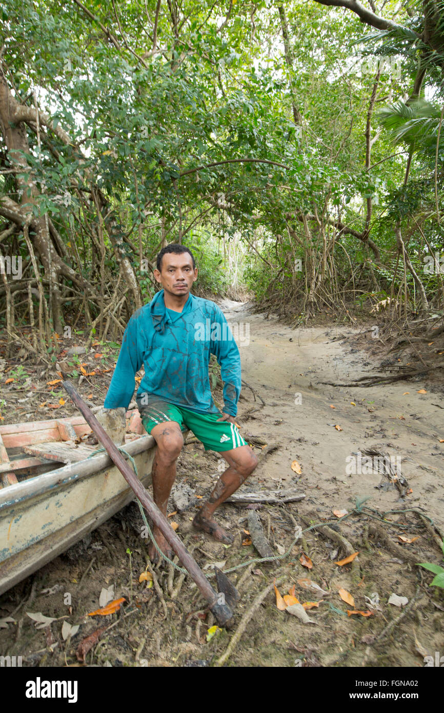 Un caboclo locale pescatore seduto su una scavata canoa, Marajo island [Ilha do Marajo] in una foresta di mangrovie, l'Amazzonia brasiliana Foto Stock