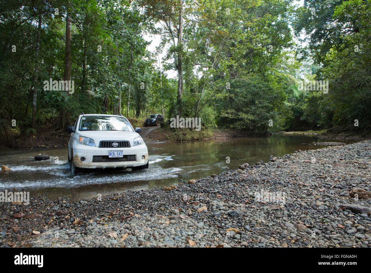 Un'auto bianca di ritorno che attraversa un fiume sulla penisola di Nicoya, guida fuoristrada, foresta pluviale selvaggia, Nicoya, Puntarenas, Costa Rica Foto Stock