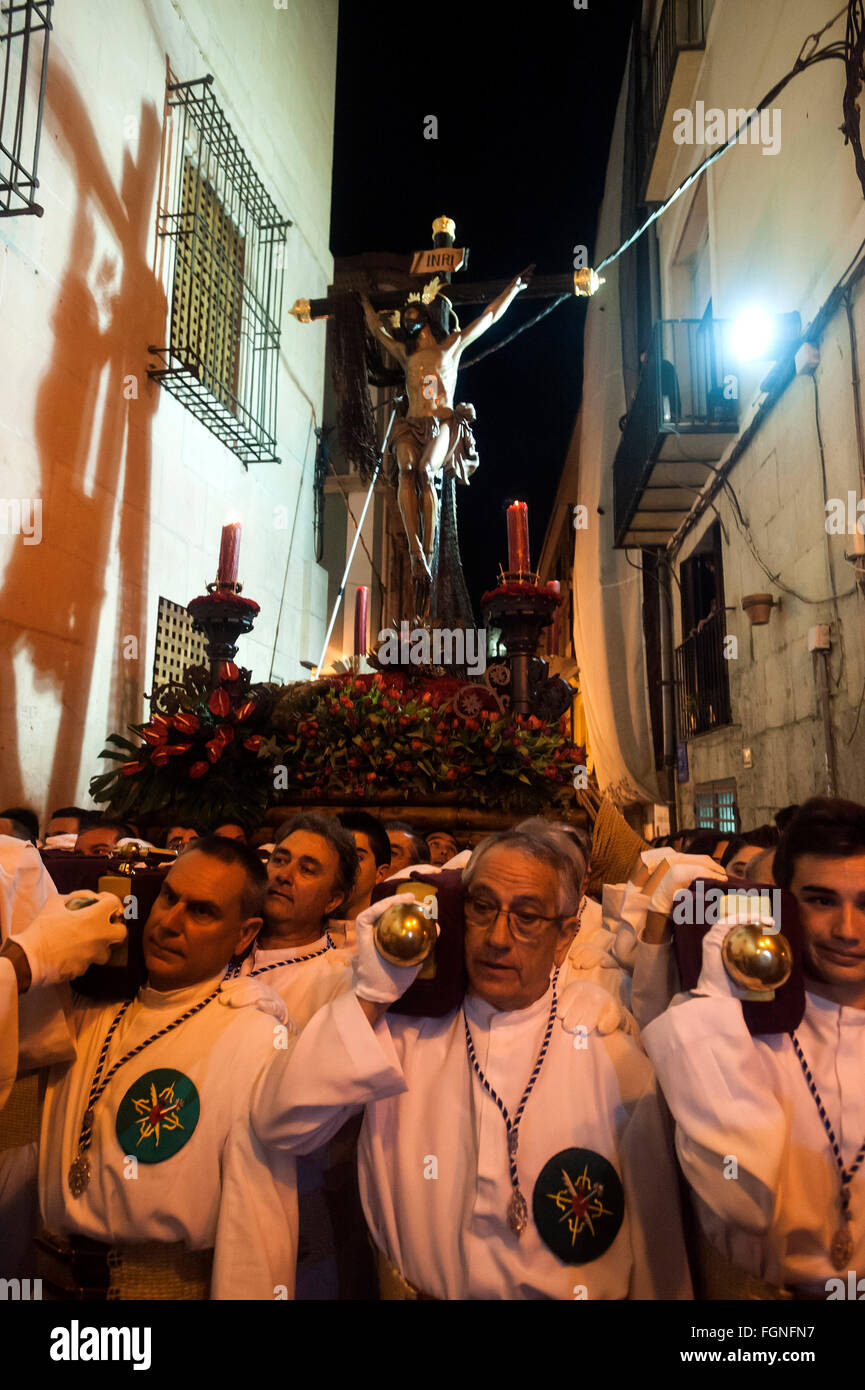 Il costaleros della confraternita di Santa Croce nella processione a mare di Cristo attraverso le strade della città vecchia di bianchissima l'alica Foto Stock