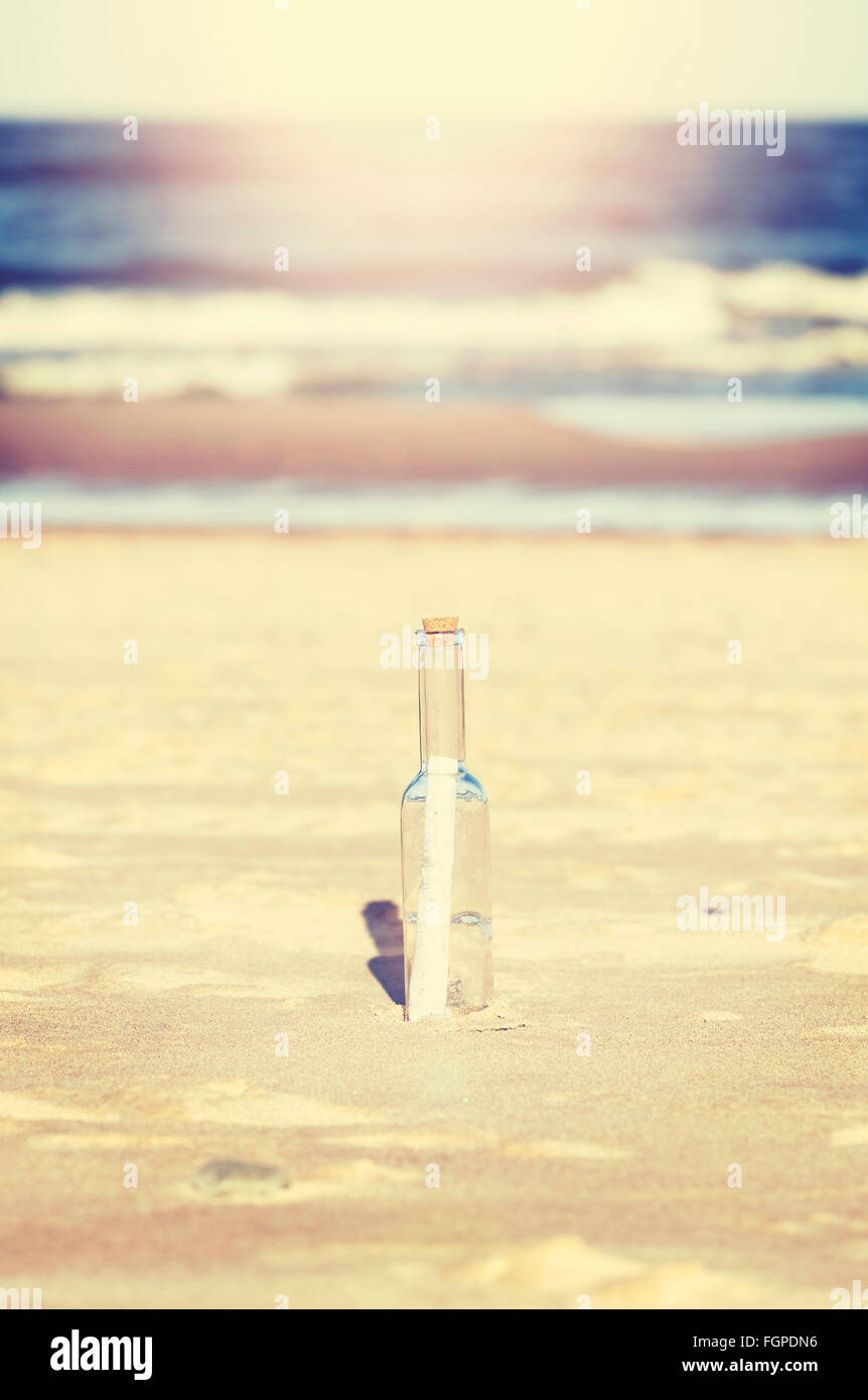 Vintage stilizzata un messaggio in bottiglia sulla spiaggia, profondità di campo. Foto Stock