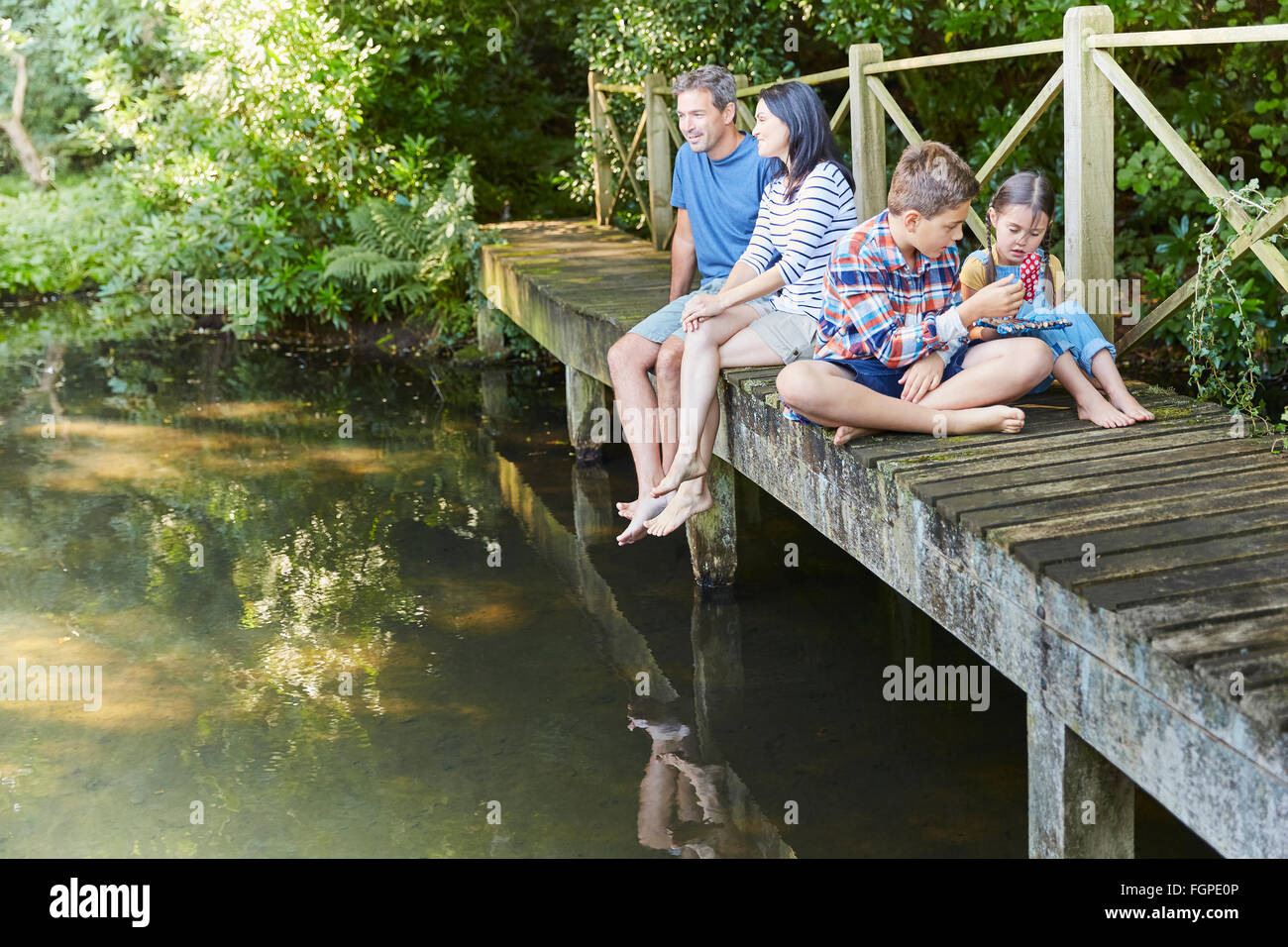 Famiglia rilassante sulla passerella sul laghetto Foto Stock