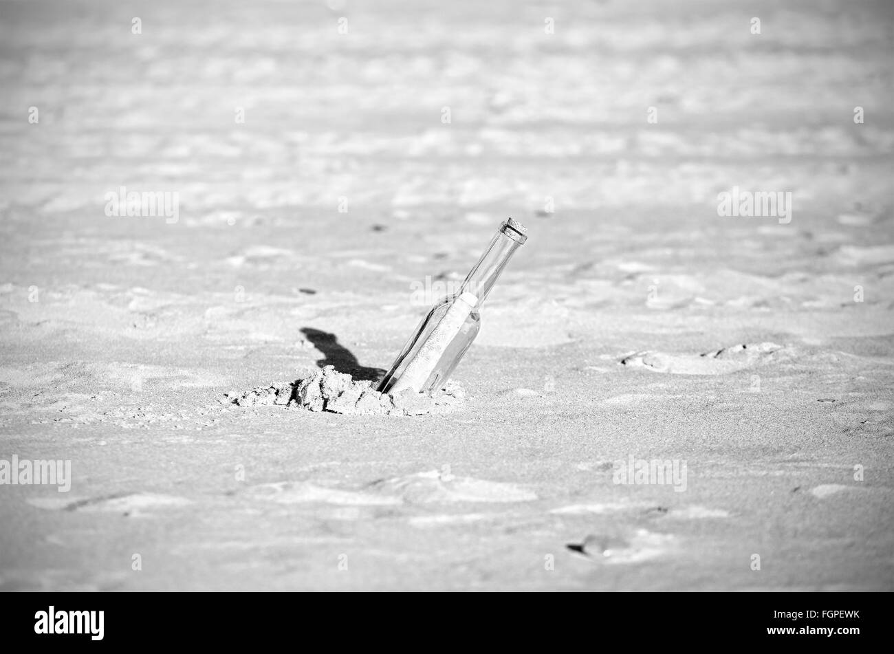 In bianco e nero un messaggio in bottiglia sulla sabbia, profondità di campo. Foto Stock