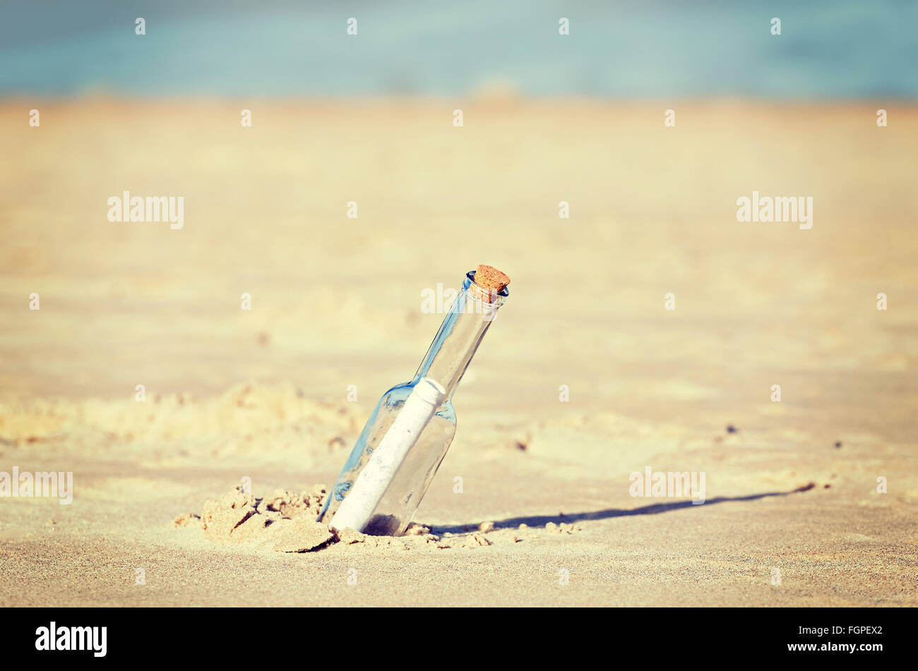 Dai toni rétro un messaggio in bottiglia sulla spiaggia, profondità di campo. Foto Stock