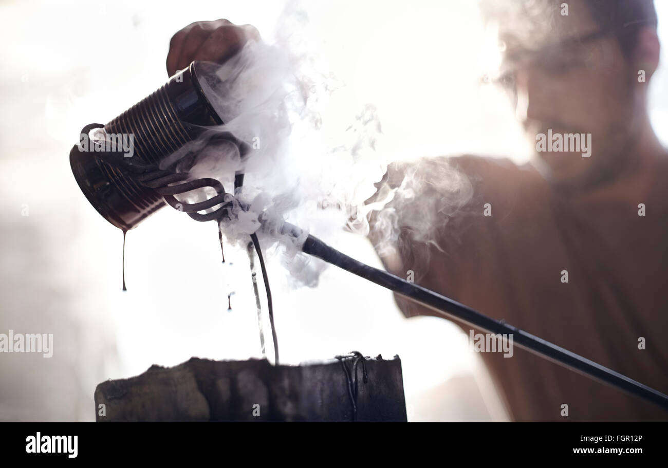 Fabbro versando il liquido di cottura a vapore su ferro battuto Foto Stock