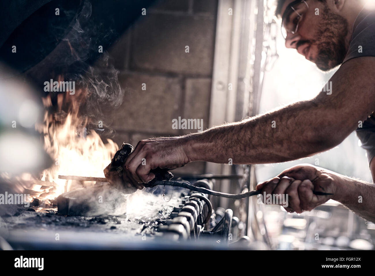 Fabbro lavora sul fuoco nel forge Foto Stock