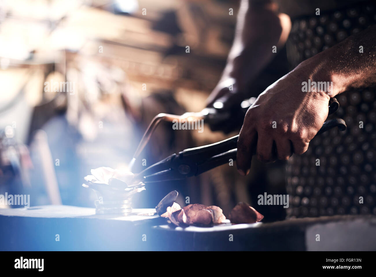 Chiusura del fabbro di metallo di riscaldamento con cannello in forge Foto Stock
