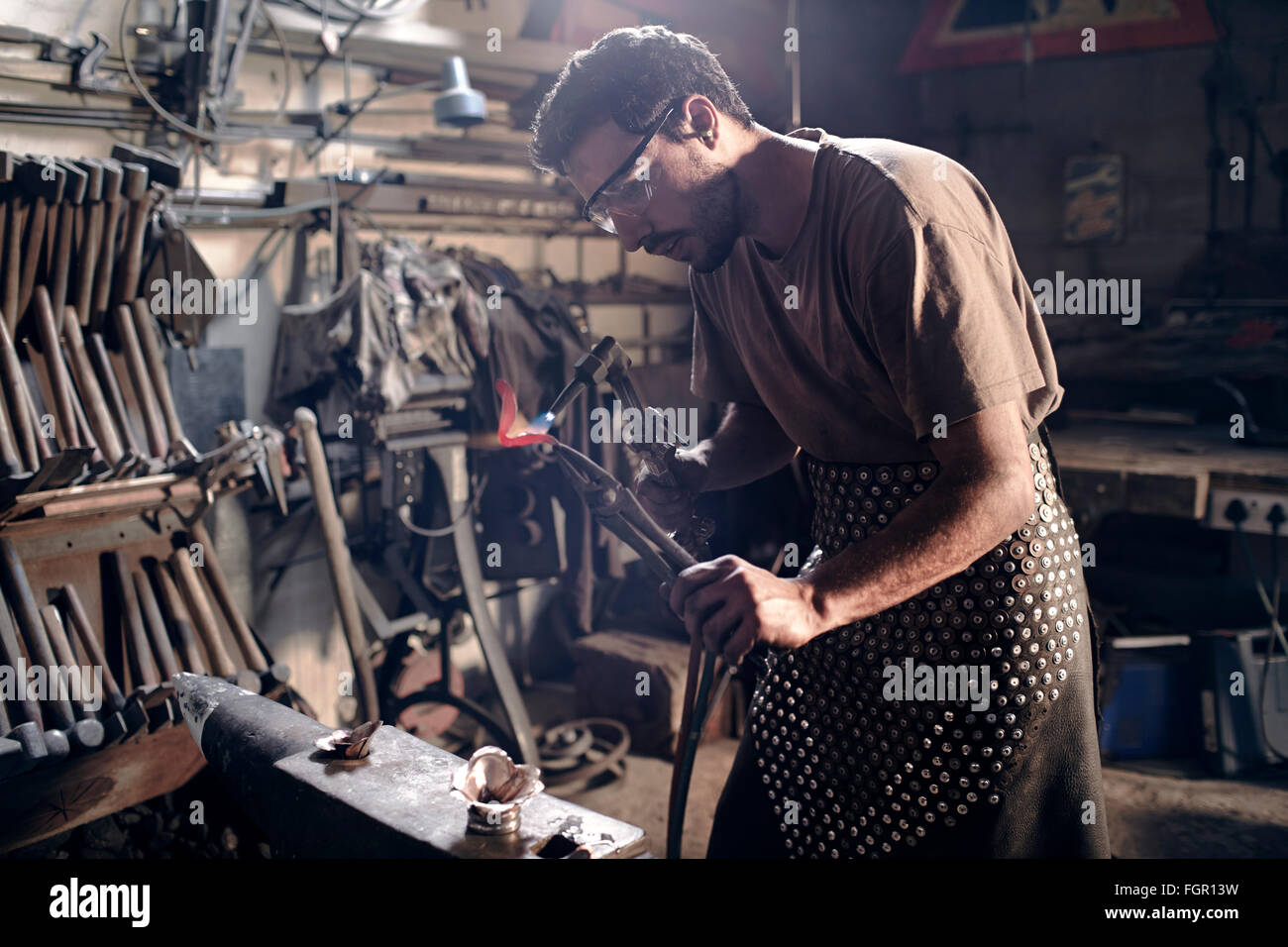 Fabbro di metallo di riscaldamento con cannello in forge Foto Stock