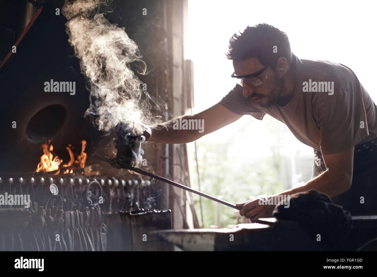Fabbro per la cottura a vapore di sagomatura del ferro battuto nella fucina Foto Stock