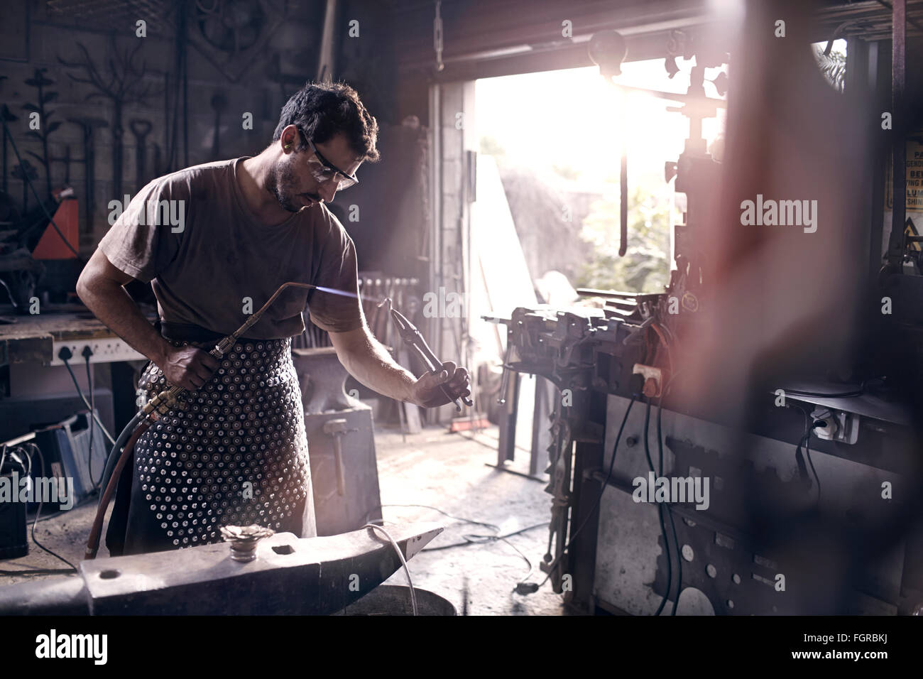Fabbro con torcia soffiante in forge Foto Stock
