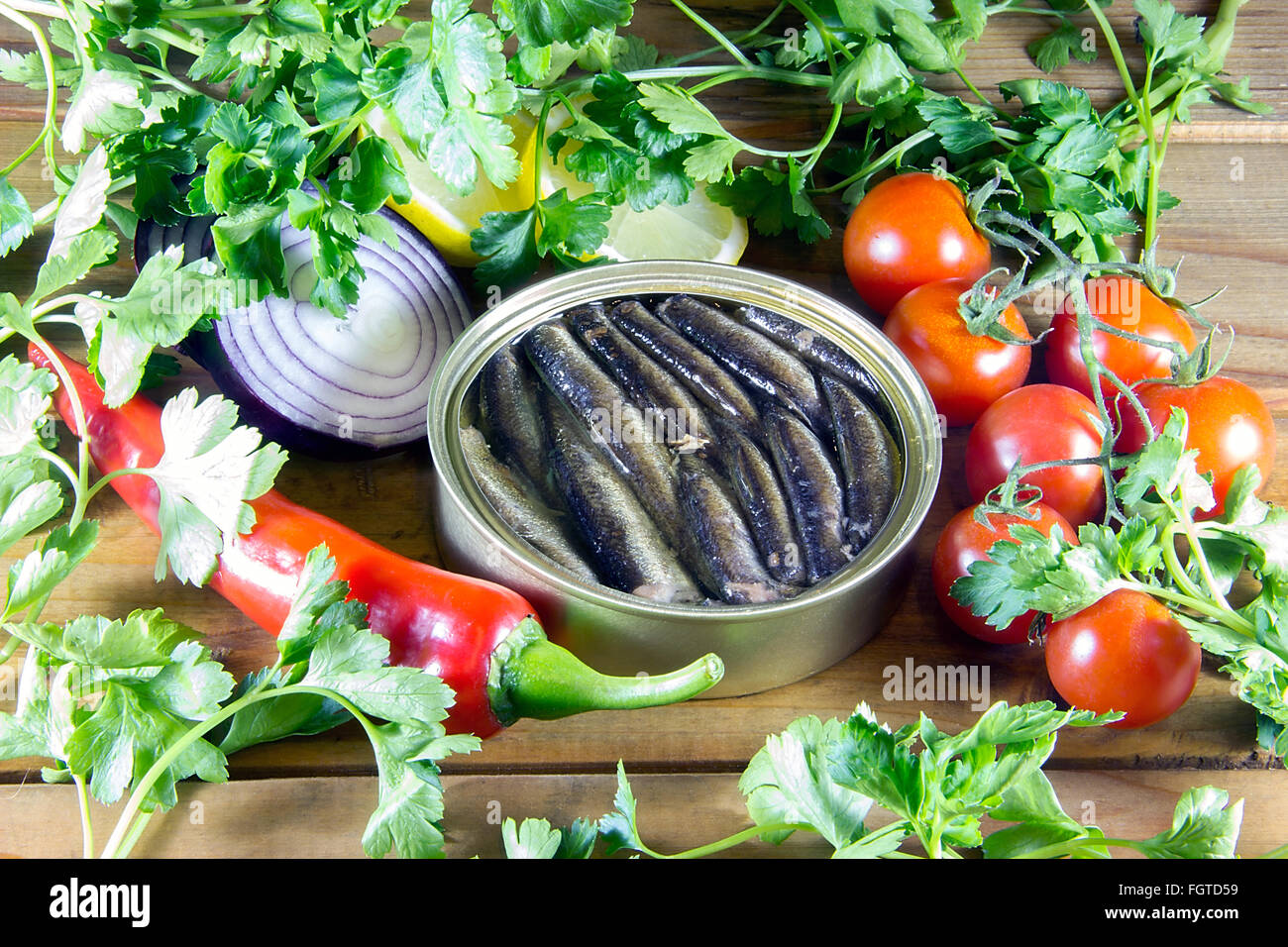 Un può di spratti e verdura sparsi su un tavolo di legno Foto Stock