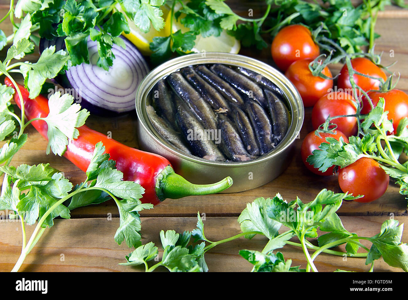 Un può di spratti e verdura sparsi su un tavolo di legno Foto Stock