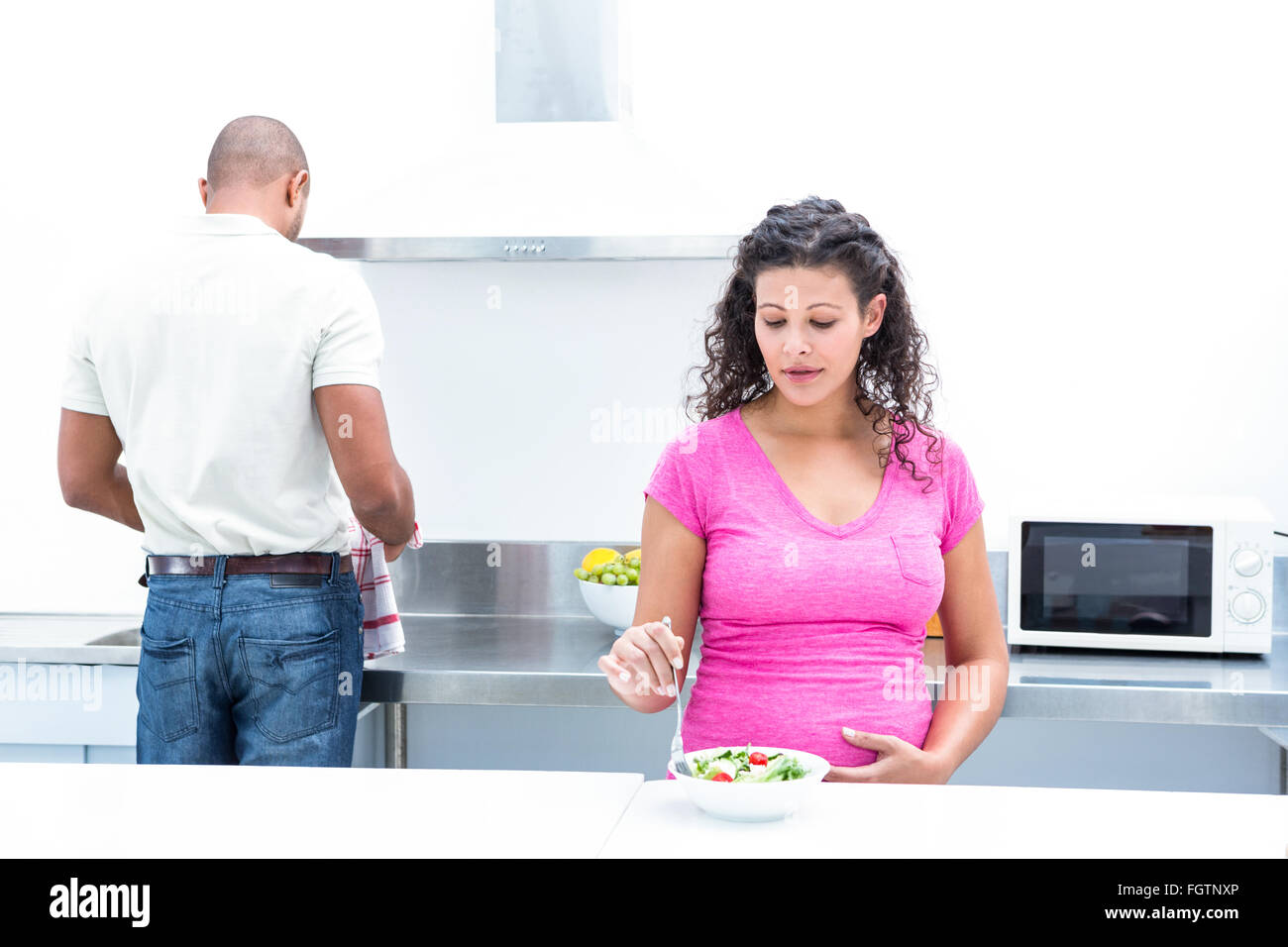 Il marito aiutando moglie incinta in cucina Foto Stock