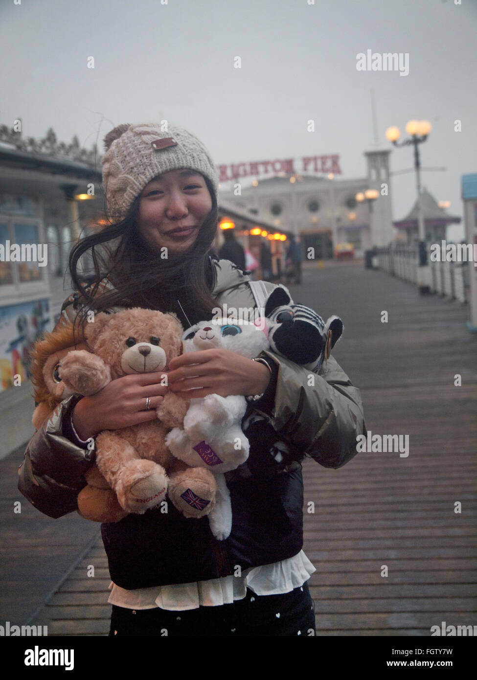 Un turista sul molo di Brighton con i giocattoli morbidi che lei ha appena vinto Foto Stock