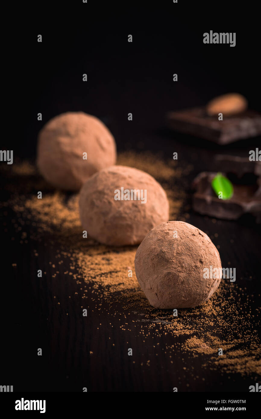 Tartufi di cioccolato sulla piastra nera su sfondo nero. Dessert di lusso, vellutata tartufi di cioccolato Foto Stock