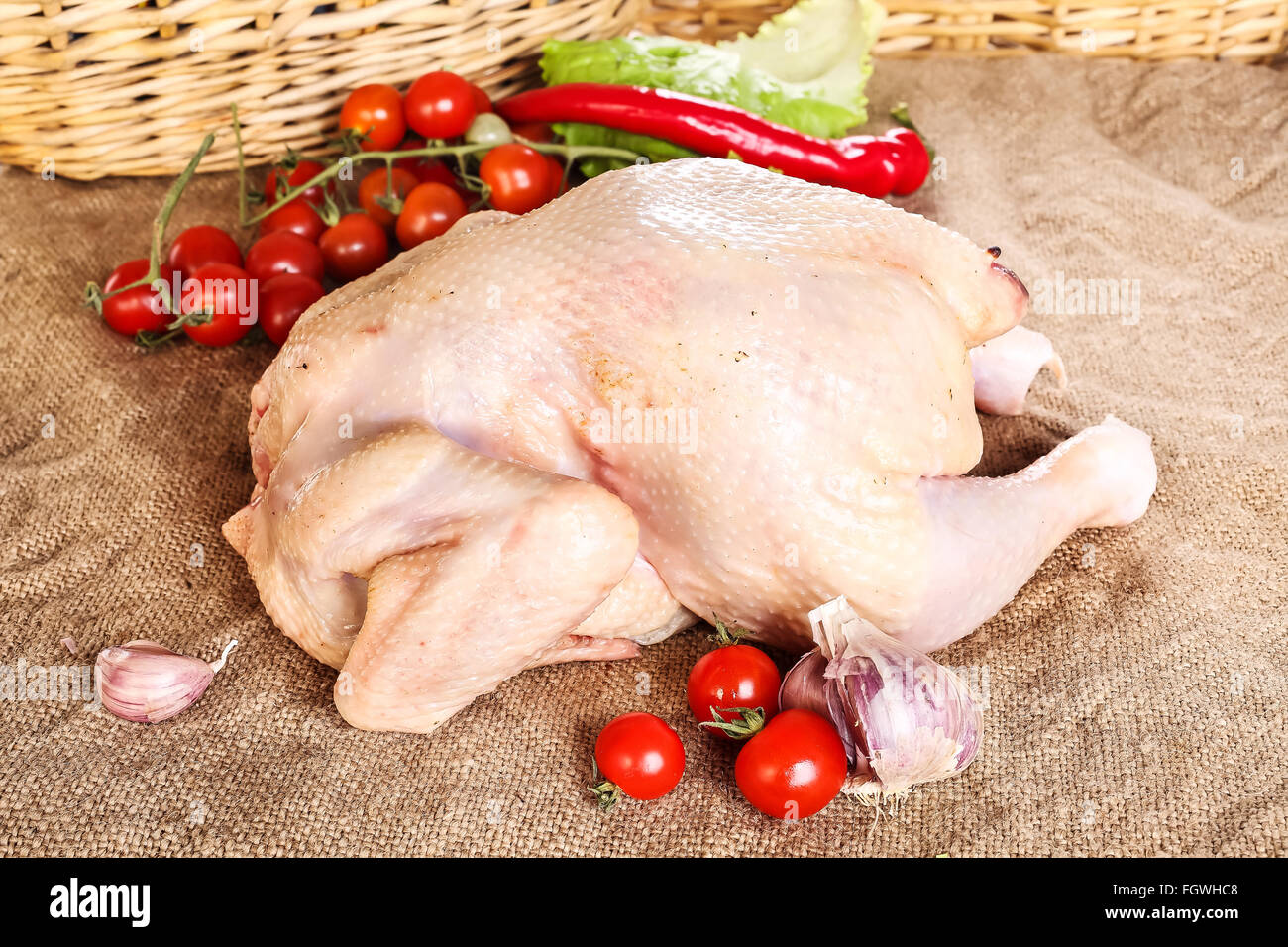 Crudo fresco carcassa di pollo tavola di legno con pomodoro Foto Stock