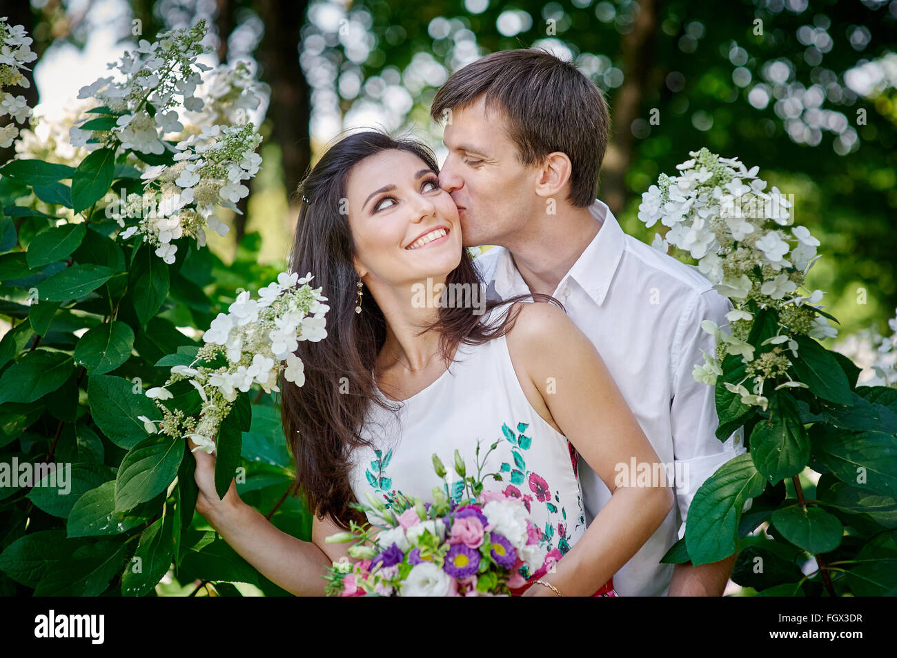 Elegante lo sposo con la sua sposa felice baci nel parco Foto Stock