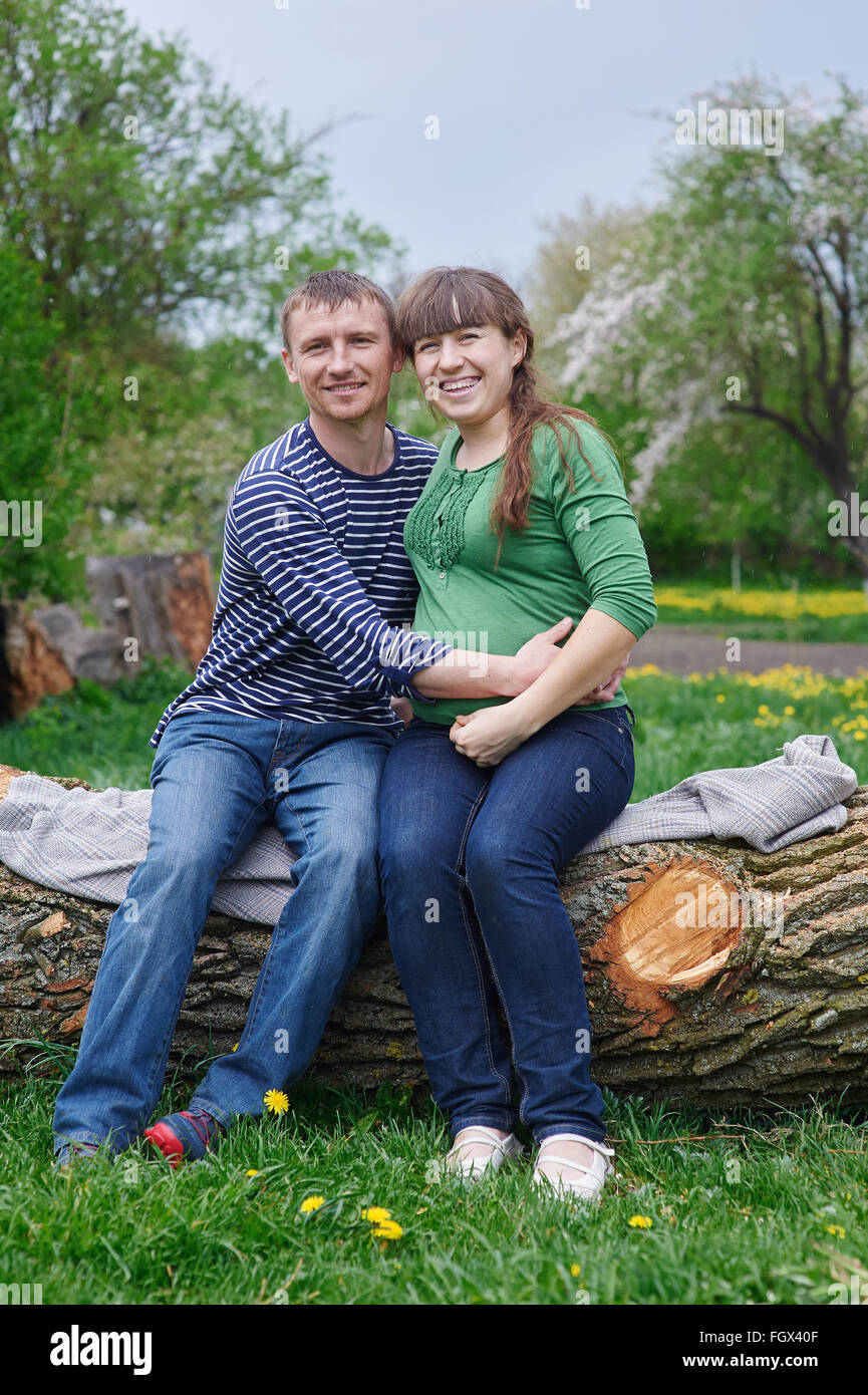 Il marito e la moglie incinta seduta su un ponte di legno Foto Stock