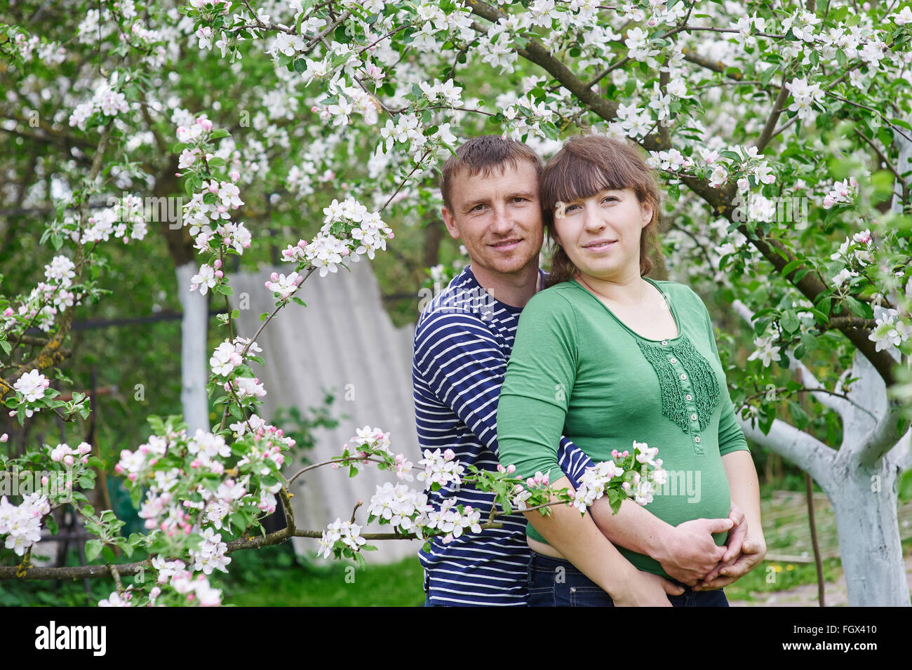 Il marito e la moglie incinta nella primavera giardino fiorito Foto Stock