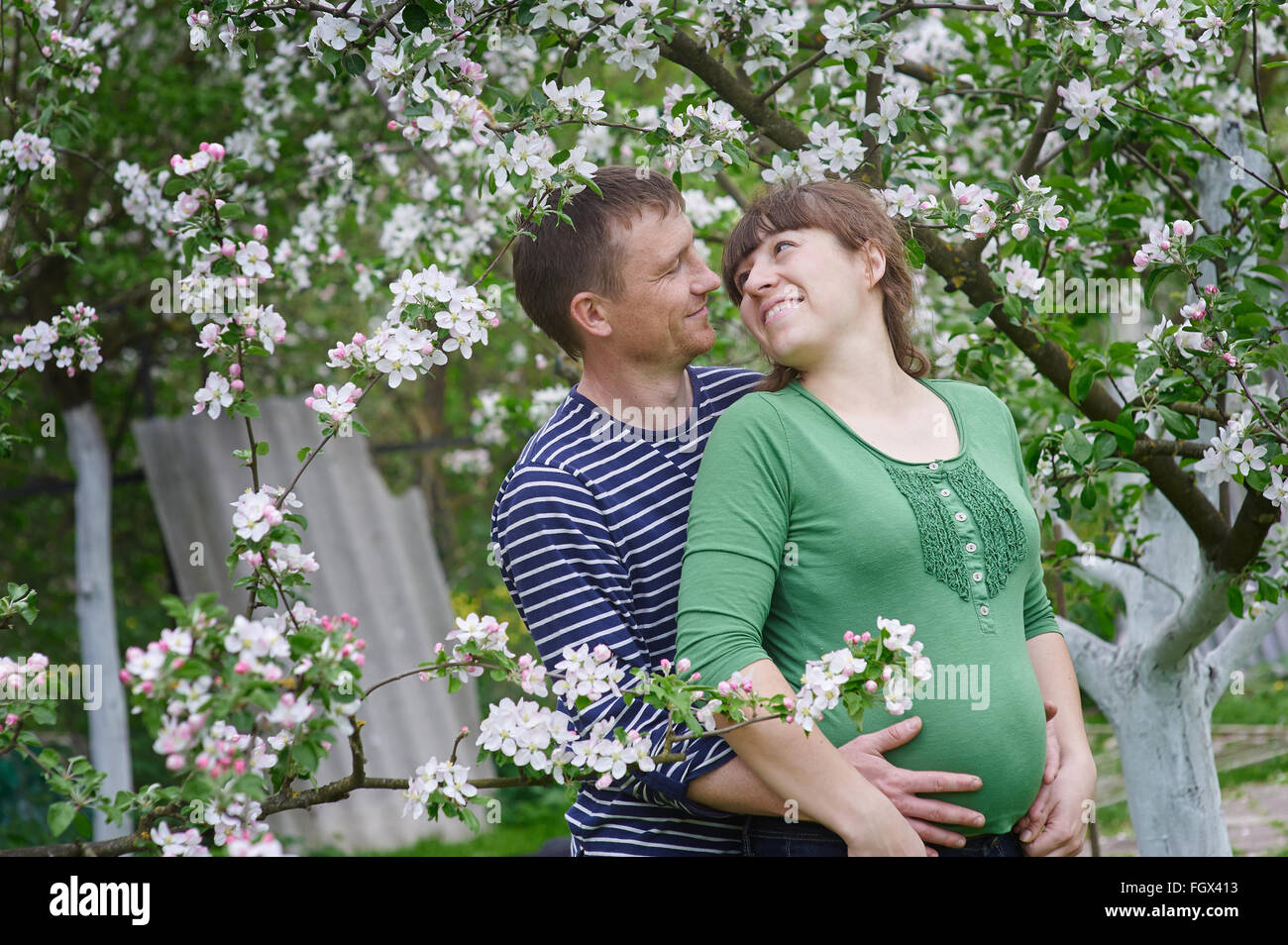 Il marito e la moglie incinta nella primavera giardino fiorito Foto Stock