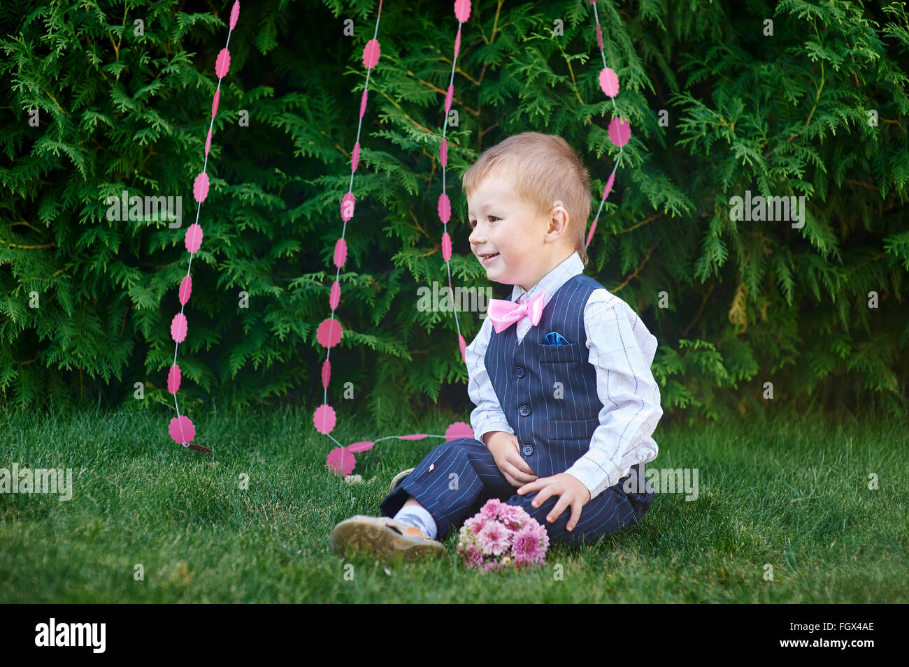 Little Boy in un vestito con un bouquet seduto sull'erba Foto Stock