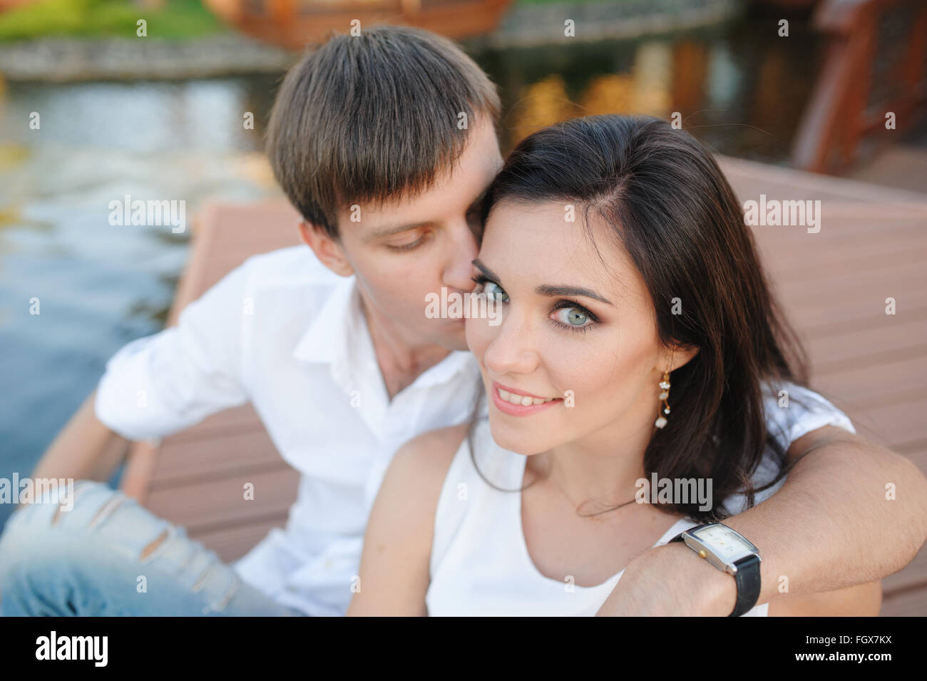 Uomo di baciare una bella donna sulla guancia giovane Foto Stock