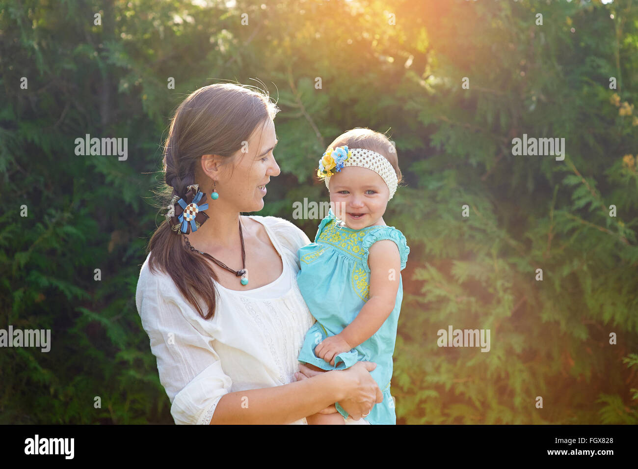 Mom mantiene la figlia nelle sue braccia e gioca sulla natura Foto Stock