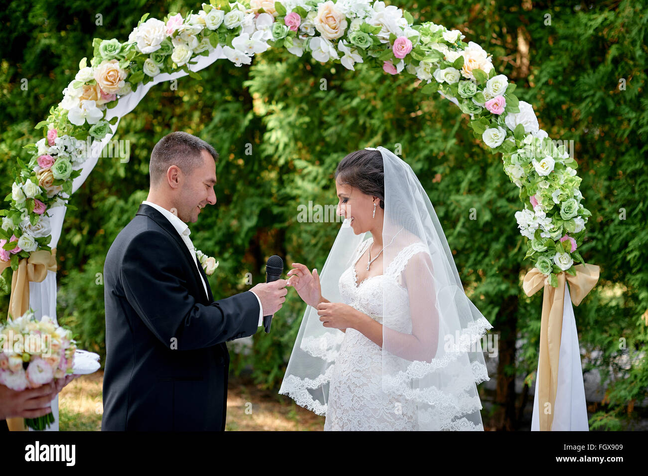 Sposa sposo abiti un anello su un dito in corrispondenza di una cerimonia di matrimonio Foto Stock