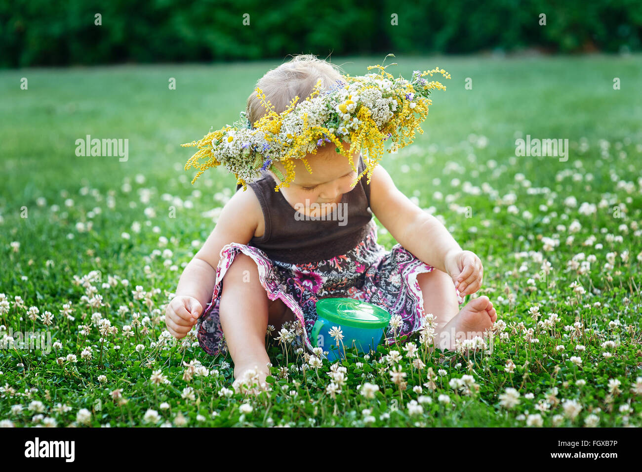 Splendido piccolo felice bambina in una corona di fiori su un prato sulla natura Foto Stock