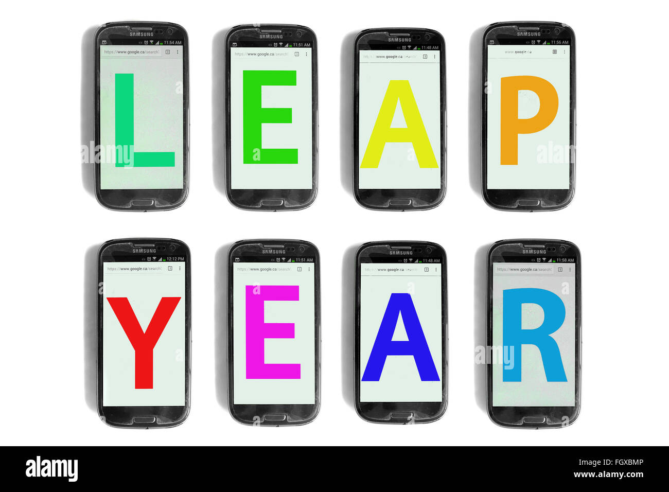 Anno bisestile scritto su schermi di smartphone fotografati contro uno sfondo bianco. Foto Stock