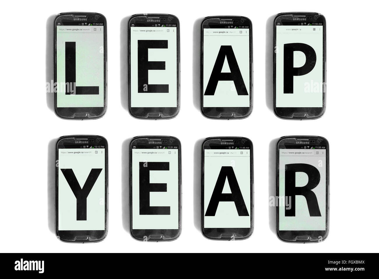 Anno bisestile scritto su schermi di smartphone fotografati contro uno sfondo bianco. Foto Stock