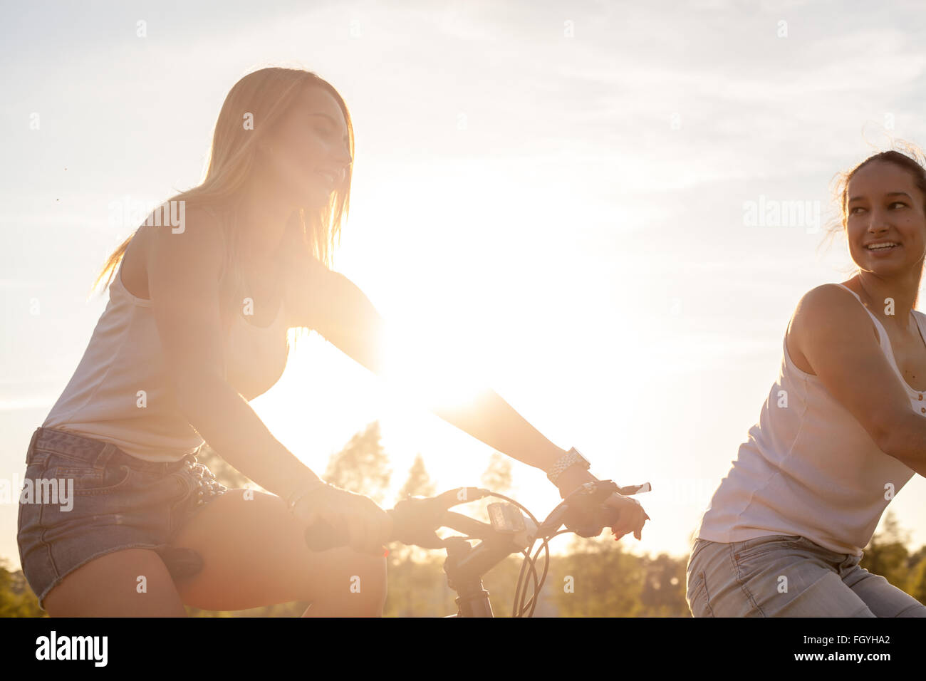 Due giovani graziosi sorridenti belle ragazze che indossano bianco casual canotte e jeans corti riding bike park Foto Stock