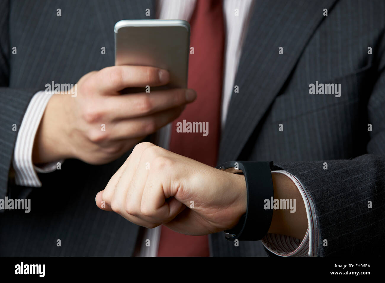 Imprenditore sincronizzazione orologio intelligente con il telefono cellulare Foto Stock