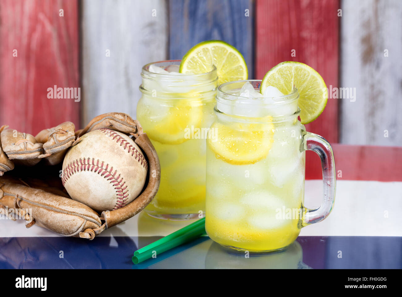 Close up di bicchieri riempiti con limonata fredda con Guanto baseball e la sfera. Foto Stock
