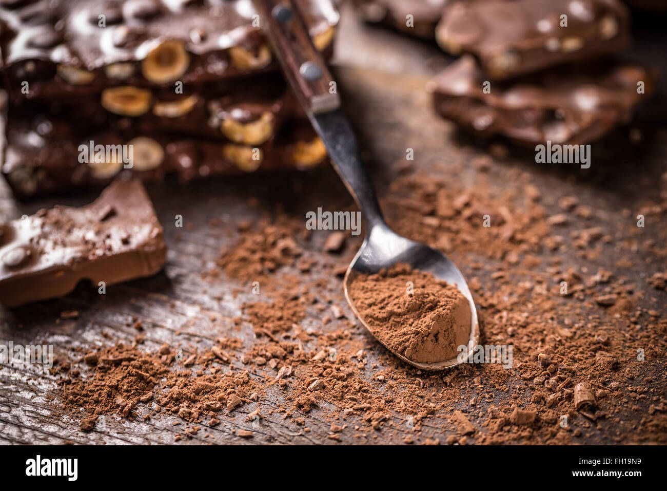 Cacao in polvere sul cucchiaio, cioccolato in background Foto Stock