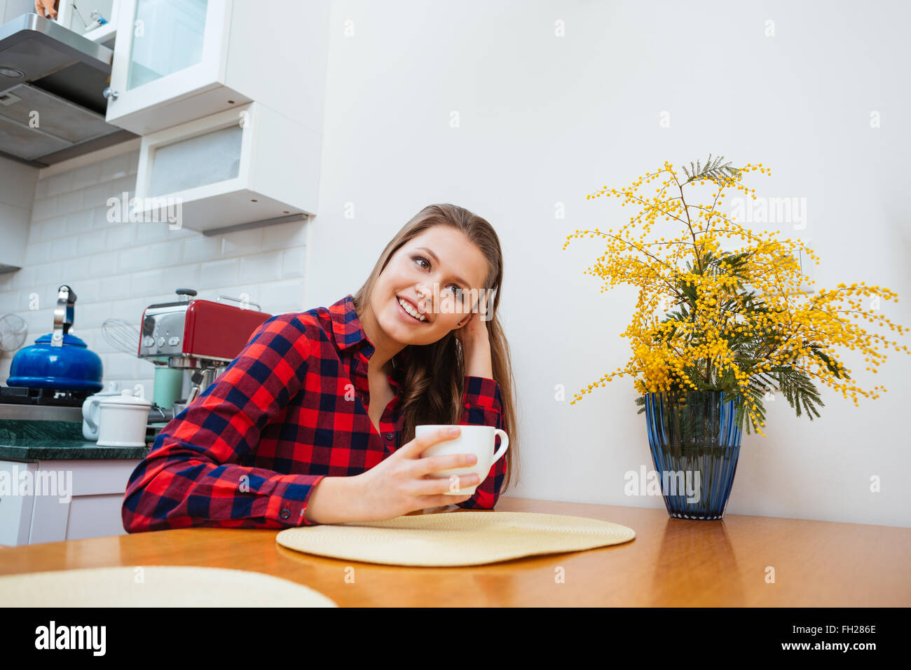 Allegro piuttosto giovane donna di bere il caffè in cucina a casa Foto Stock