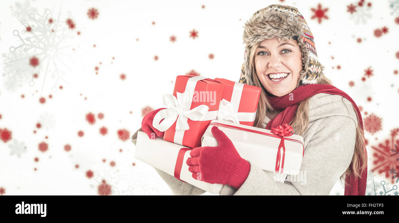 Immagine composita di felice bionda in inverno abiti regali di contenimento Foto Stock