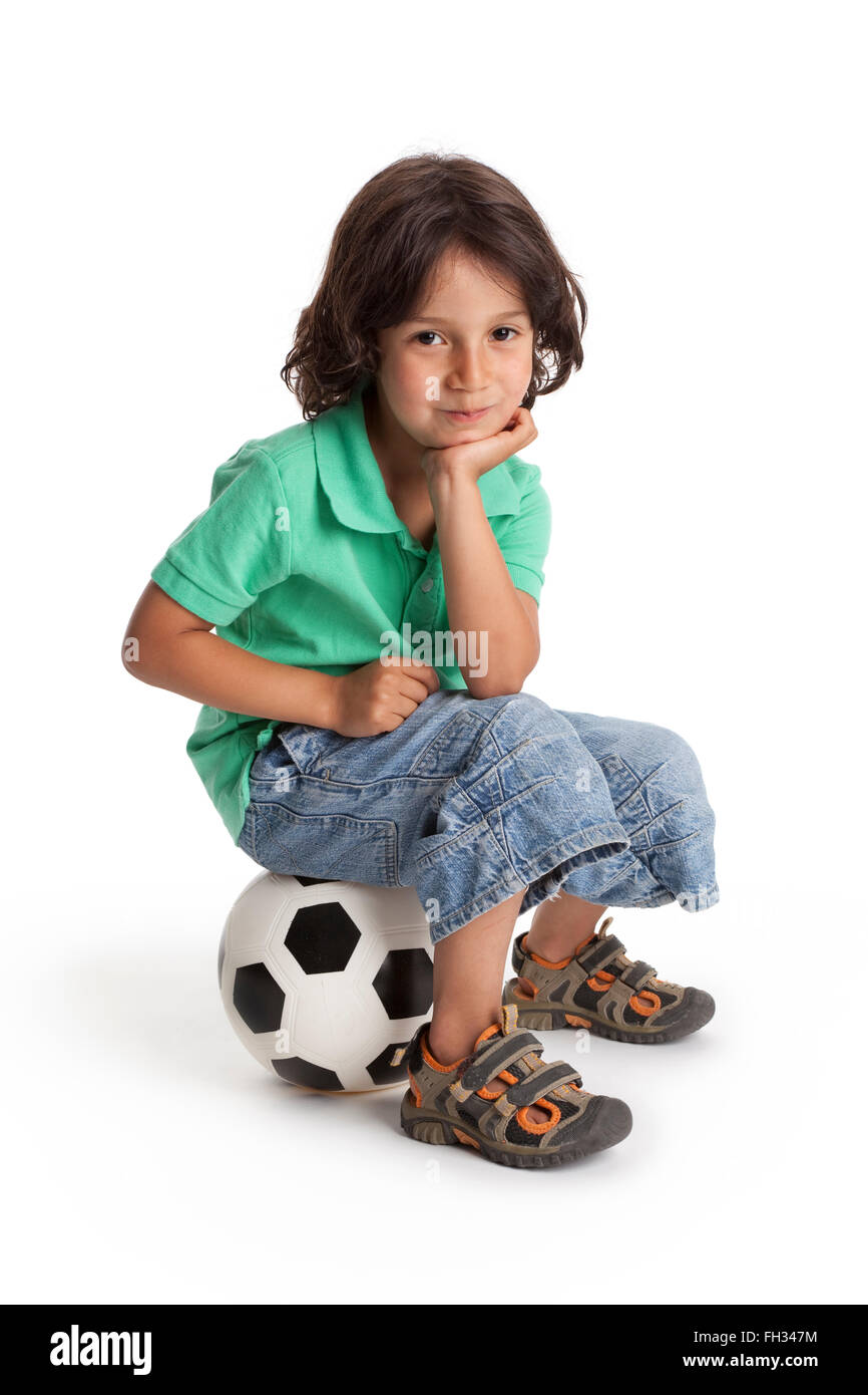 Sorridente ragazzino seduto su un pallone da calcio su sfondo bianco Foto Stock