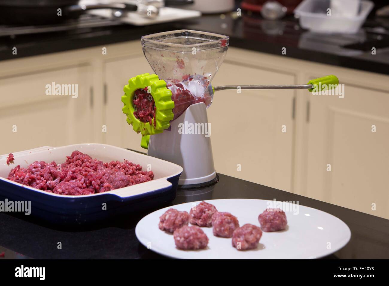 Un tritacarne o mola è utilizzato sulla carne di manzo crudo per preparare gli ingredienti per le polpette di carne in una famiglia cucina di paese. Foto Stock